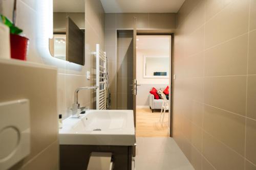 Elle comprend un salon et une salle de bains pourvue d'un lavabo blanc. dans l'établissement Stunning Modern Red Apartment near Bastille-Marais, à Paris