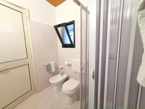 a white bathroom with a toilet and a window at Casa Colonica Liliane B&B in Porto Cesareo