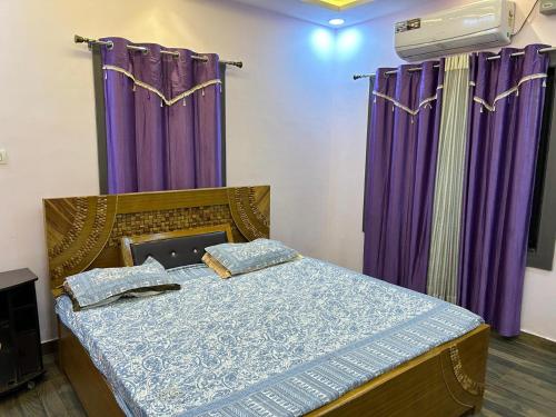 a bed in a room with purple curtains at Duja Homes in Maihar