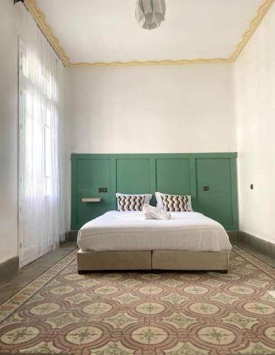 a bedroom with a large bed with a green headboard at Charming apartment in Central Medina of Tetuan15 min airport in Tetouan