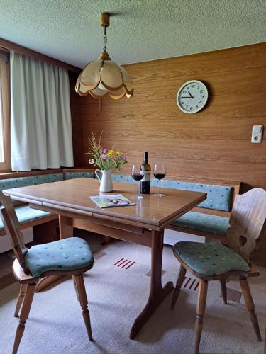 a dining room table with two chairs and a clock at Familienfreundliches Bregenzerwälderhaus in Au im Bregenzerwald