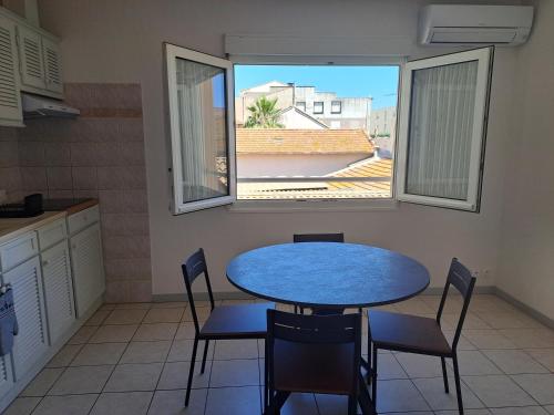 une table et des chaises dans une cuisine avec une fenêtre dans l'établissement L'Oustal de Provence, à Sète