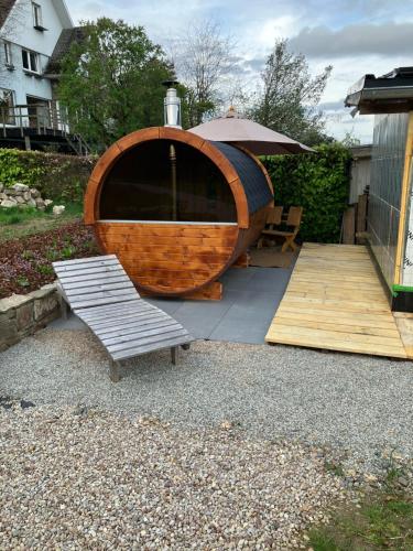 a wooden boat with an umbrella and a bench at Terrier Ovifat - logement familial Nature et Sauna in Ovifat