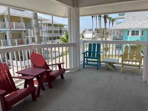 a porch with three chairs and a table on it at Seashell Village Resort near the beach with kitchens in Port Aransas