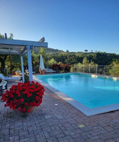 a swimming pool with a bunch of red flowers next to it at Agriturismo La Gioconda in Vinci