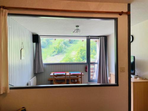 a room with a table and a large window at Studio pied de pistes Tour de la Biche in Besse-et-Saint-Anastaise