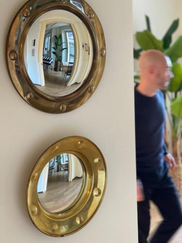 a man walking past a gold mirror on a wall at Murè Hotel Numana in Numana