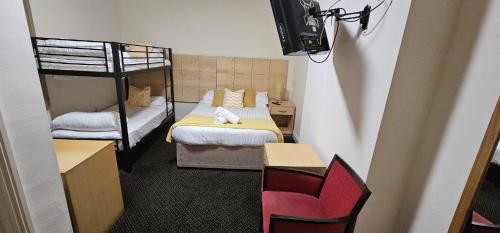 a small room with two bunk beds and a red chair at Brooklands Lodge in Bournemouth