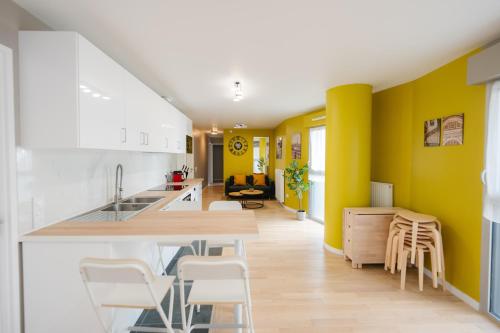 une cuisine avec des murs jaunes et un comptoir avec des tabourets dans l'établissement Confort Absolu à Paris ,superbe appartement rénové 7 Chambres avec salles de Bain privatives, à Paris