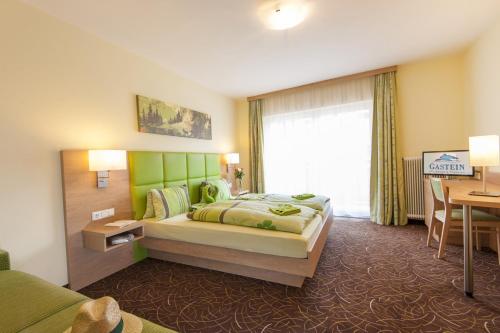 a bedroom with a bed with a green headboard and a desk at Kaiser-Franz in Bad Hofgastein