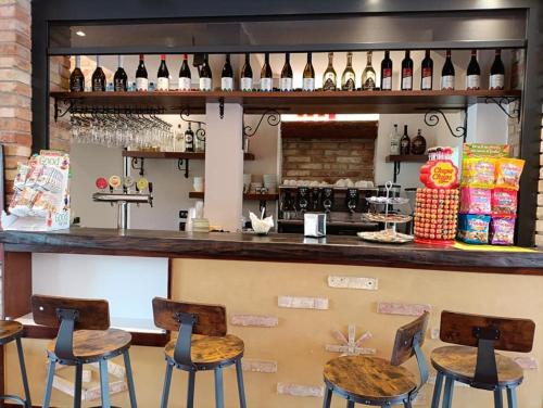 a bar with four stools and bottles of wine at Hotel Residence - Il Giardino del Cigno in Latisana