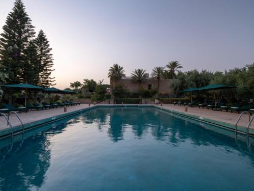 a swimming pool in a resort with chairs and umbrellas at Kasbah Agafay Hotel & Spa in El Karia