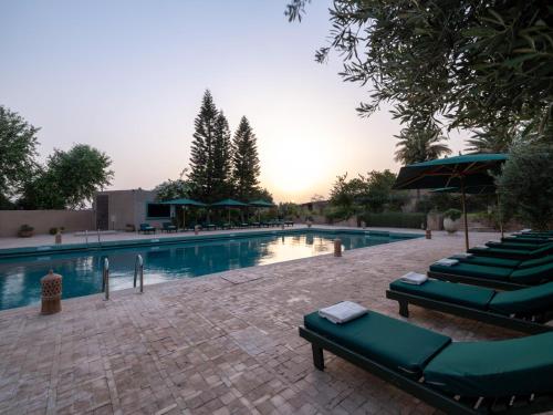 a swimming pool with green lounge chairs and umbrellas at Kasbah Agafay Hotel & Spa in El Karia
