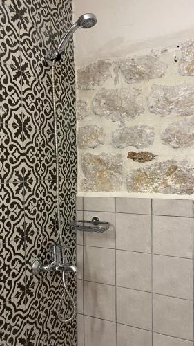 a shower in a bathroom with a stone wall at Eternia Suites in Katakoúli