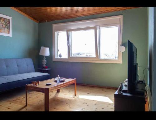 a living room with a blue couch and a coffee table at kali SunnySide Up in Nea Kalikratia