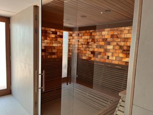 a glass shower in a bathroom with a stone wall at Spa Residence Carbona 101, 307 Apartman in Hévíz