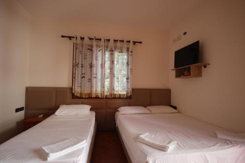 two twin beds in a room with a window at Vila Bajrami in Vlorë