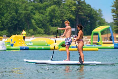 two people standing on a paddle board in the water at Aloha Beach Resort in Wisconsin Dells