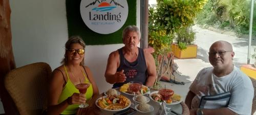 a group of three people sitting at a table with food at The Landing Hotel And Restaurant in Moyogalpa