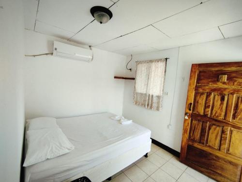 a small bedroom with a bed and a door at The Landing Hotel And Restaurant in Moyogalpa