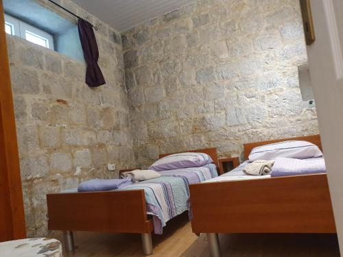 two beds in a room with a stone wall at Apartments Eldi in Split