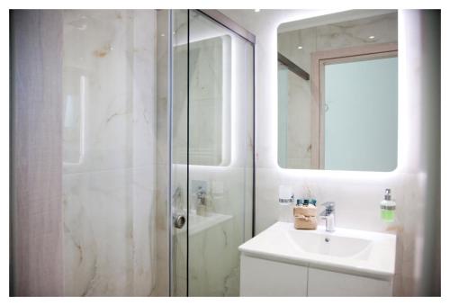 un bagno bianco con lavandino e doccia di Ammoshine Apartment a Néa Péramos