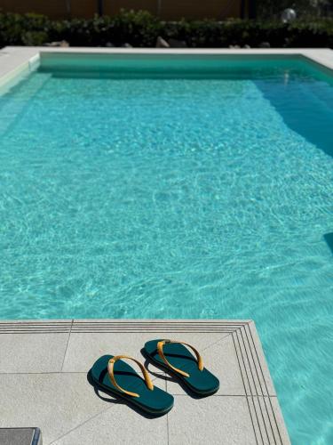 a pair of flip flops sitting next to a swimming pool at Sun Holidays Home in Marina di Modica