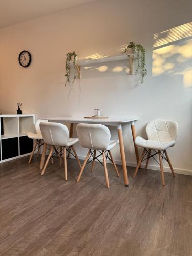 a dining room with a table and chairs and a clock at RK Apartment Brno in Brno