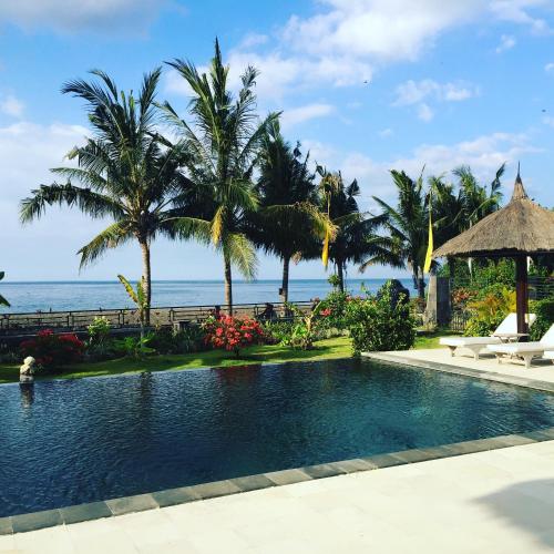 a swimming pool with the ocean in the background at Villa Danison in Umeanyar