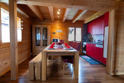 cocina con mesa de madera y armarios rojos en Chalet Regenbogen Leukerbad mit Indoorrutschbahn, en Leukerbad