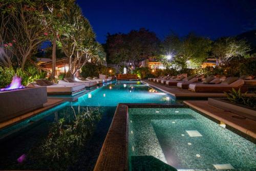 a pool with lounge chairs and a resort at night at Amomoxtli in Tepoztlán