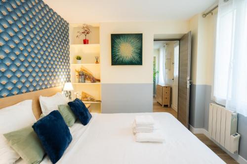 une chambre avec un grand lit blanc avec des oreillers bleus dans l'établissement Beautiful yellow apartment near Marais and Bastille, à Paris