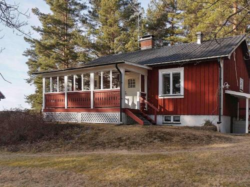 a red house with a large front porch on a yard at 4 person holiday home in ÅRJÄNG in Årjäng