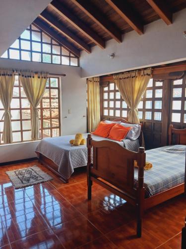 a bedroom with a bed and two windows at Chez Alicia Hostal in Villa de Leyva