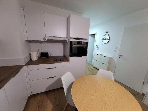 une cuisine avec une table en bois et des armoires blanches dans l'établissement Appartement proche télécabine, à Saint-Gervais-les-Bains