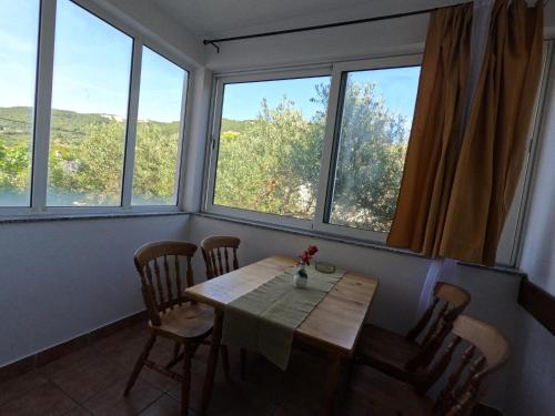 a table and chairs in a room with windows at Apartmani Daniela in Rab