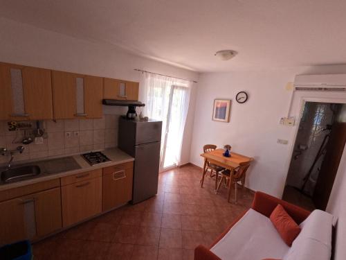 a kitchen and dining room with a table and a refrigerator at Apartmani Daniela in Rab