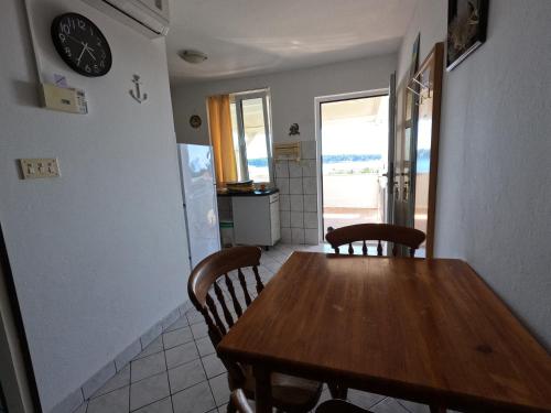 a kitchen and dining room with a wooden table and chairs at Apartmani Daniela in Rab