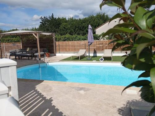 une piscine avec une table, des chaises et un parasol dans l'établissement Magnifique maison avec piscine, à Manduel
