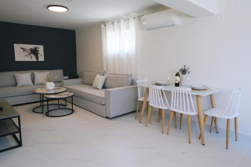 a living room with a couch and a table and chairs at Nerea Apartments in Agios Ioannis Kaspaka
