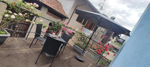 a patio with a table and an umbrella and flowers at Alex in Chambave