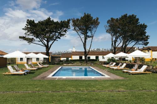 a swimming pool with lounge chairs and umbrellas at Pico do Refúgio - Casas de Campo in Ribeira Grande