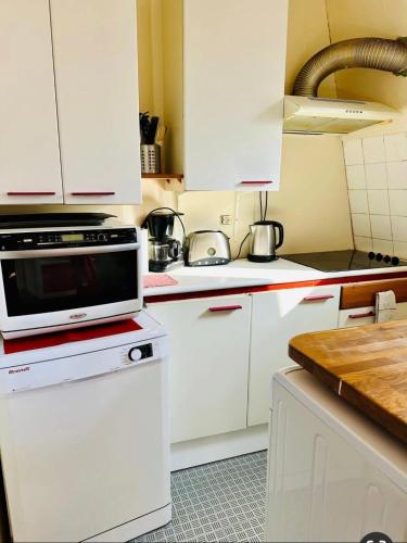 une cuisine avec des armoires blanches et un micro-ondes dans l'établissement Quiet appartment, à Paris