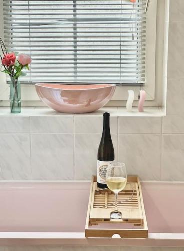 a bottle of wine and a glass on a tray at Tünde NENE Apartman in Zánka
