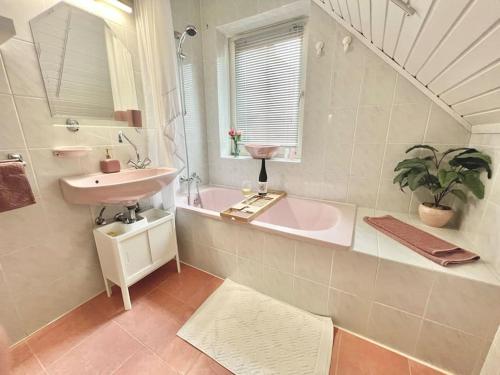 a bathroom with a sink and a tub and a mirror at Tünde NENE Apartman in Zánka