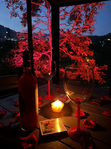 two wine glasses and a candle on a table with a window at Glamping Galcano in Dosquebradas