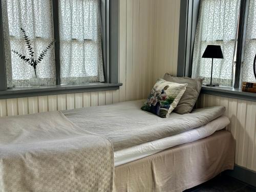 a bed sitting in a room with two windows at Lydde Gård in Kinna
