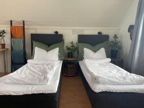 two beds with white blankets and pillows in a room at Koselig garasjeloft! in Holen