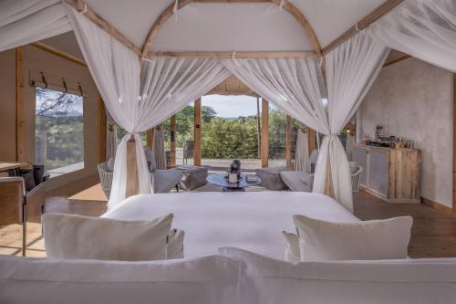 a room with a bed and chairs and windows at JW Marriott Masai Mara Lodge in Masai Mara