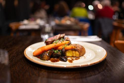 a plate of food with carrots and meat on a table at Hótel Skógafoss by EJ Hotels in Skogar
